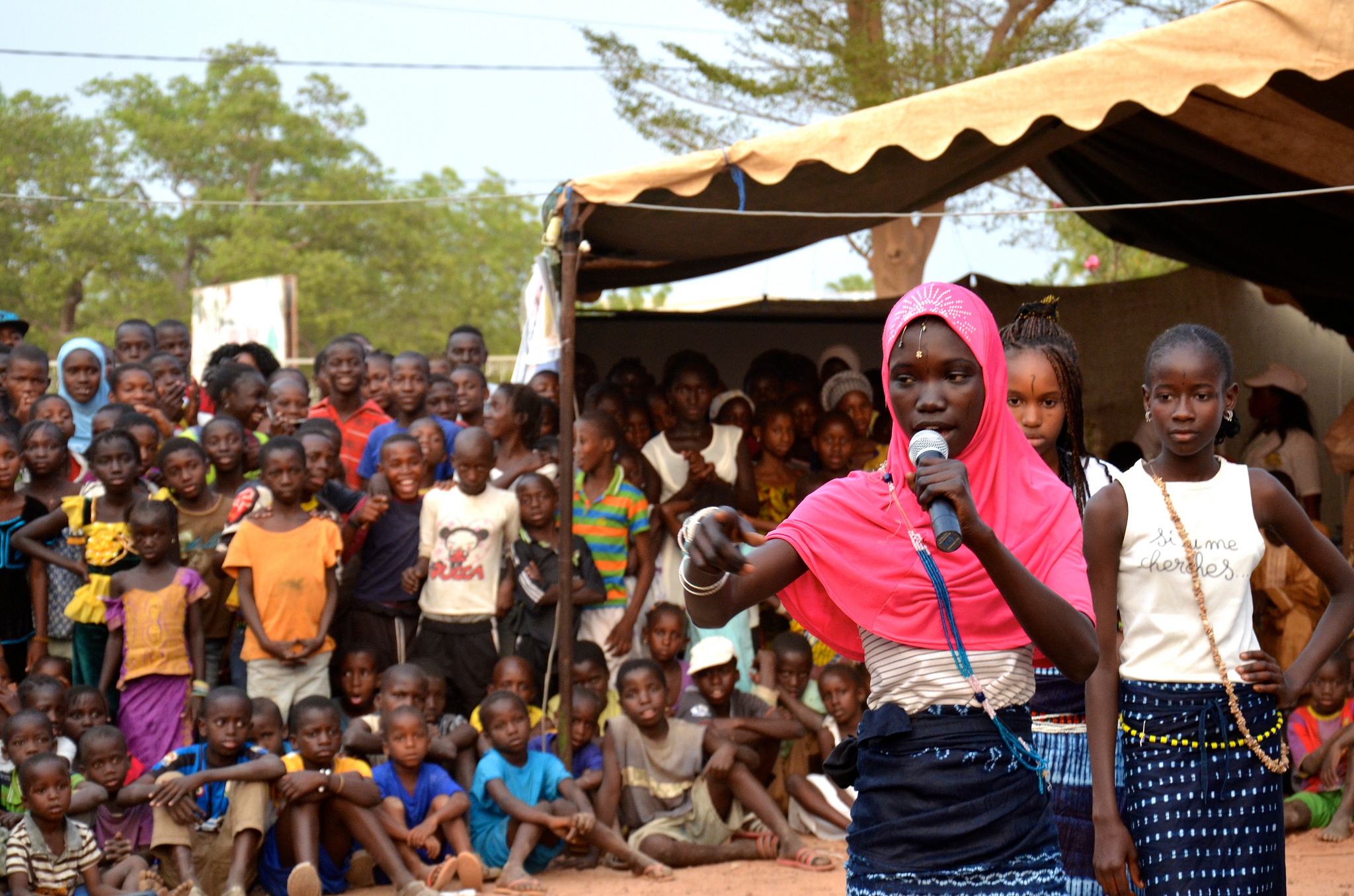 A cover picture for Youth Engagement Measurement Guideline. A young girl is speaking on a microphone and there are girl and boy children on the background.