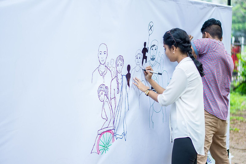 A boy and girl draw on a wall. Credit: USAID