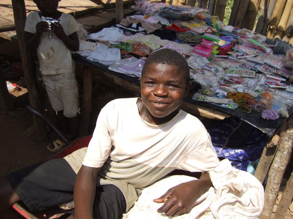 A young boy is posing in front of a shop. Youth in Liberia. Photo by Making Cents