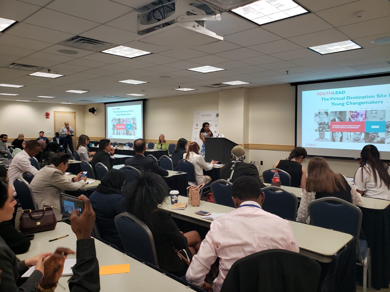 People in a meeting room with two display screens in the front